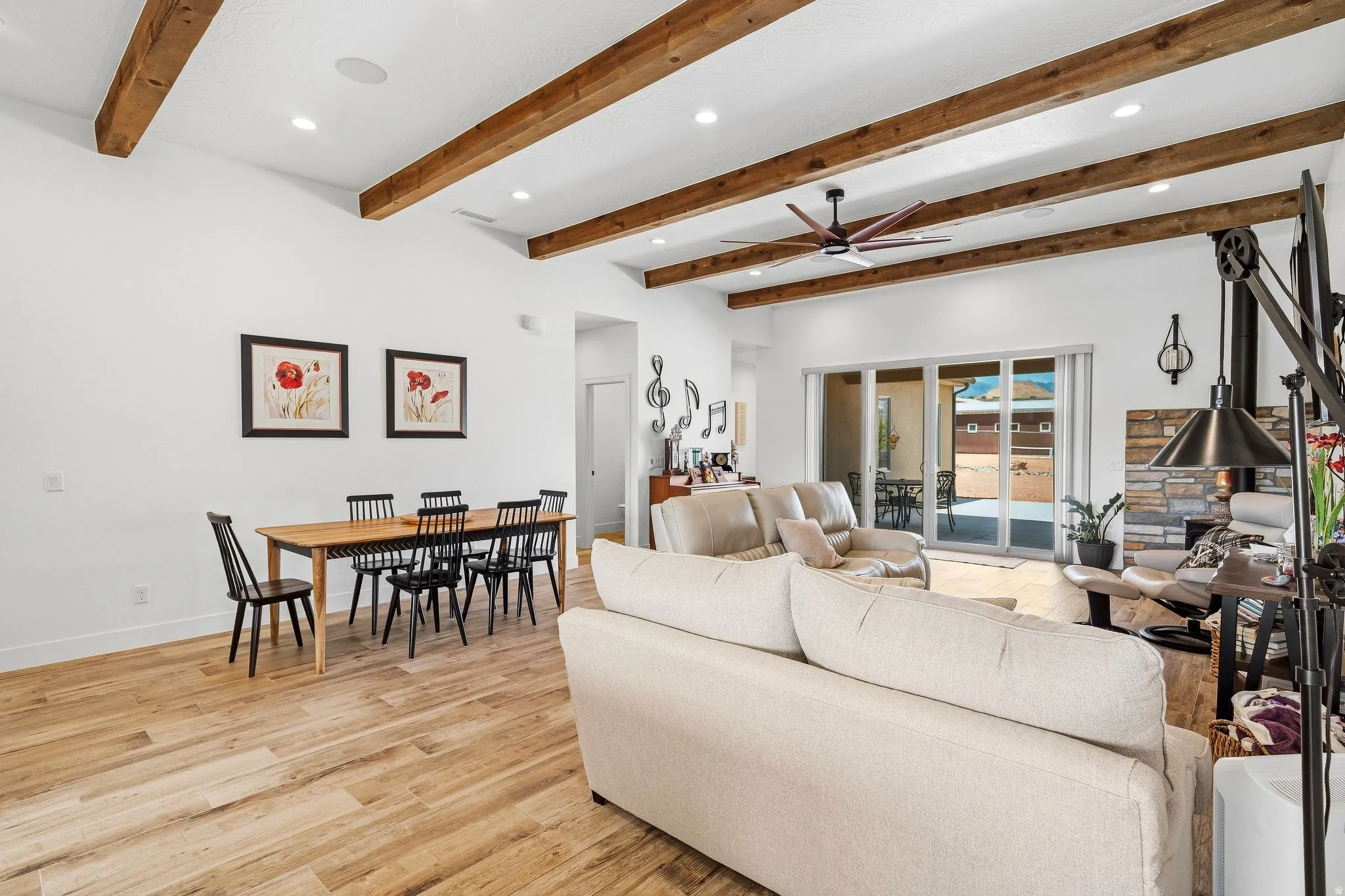Vaulted ceiling with exposed wood beams, wood-finish flooring, recessed lighting, ceiling fan, and sliding glass doors