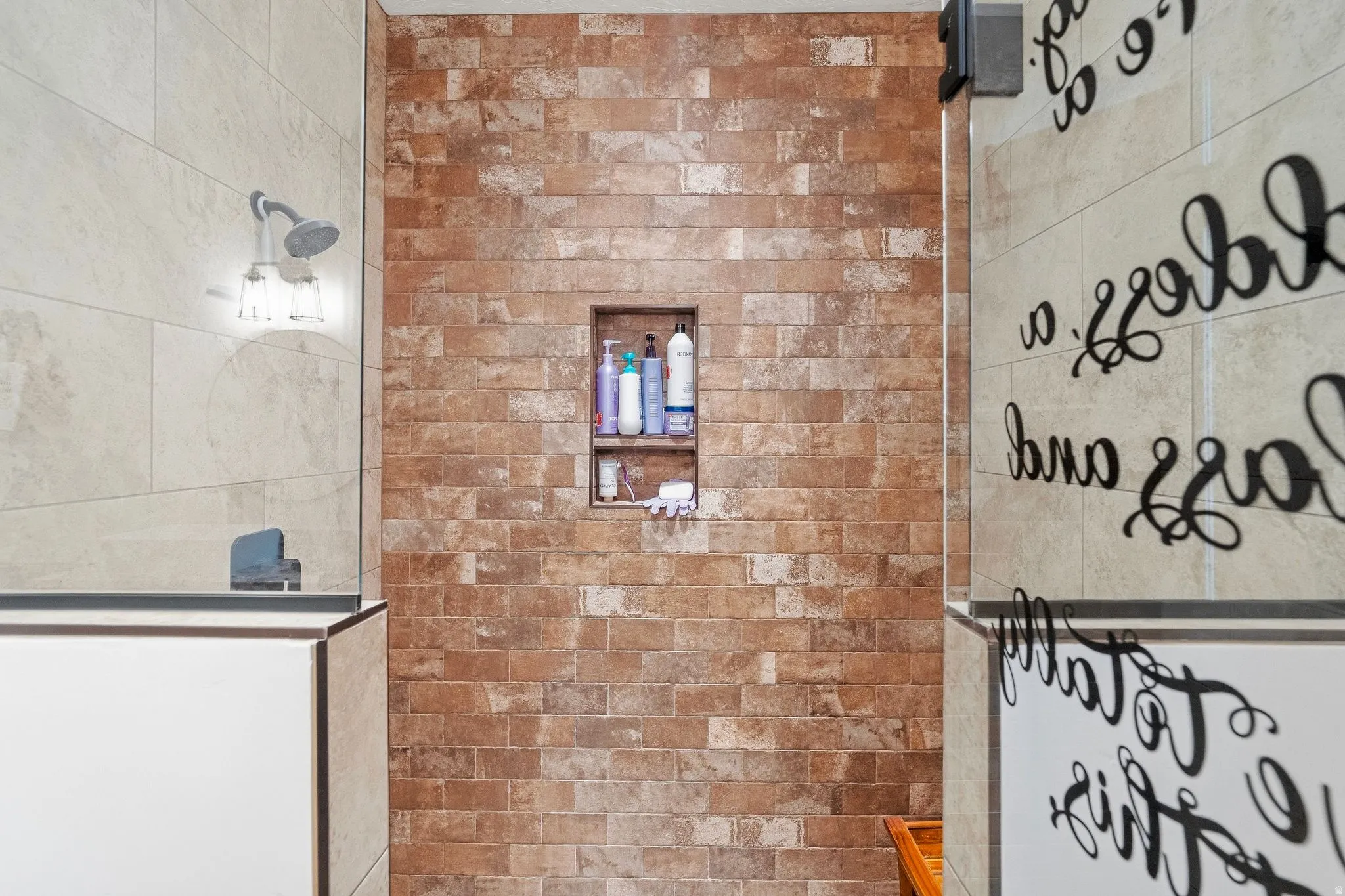 Shower with a built-in niche, brick-patterned tile, and a fixed showerhead