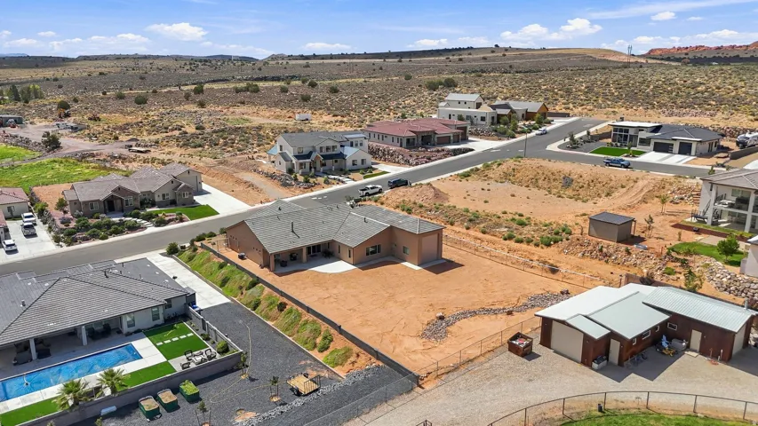Expansive property featuring a large undeveloped lot, detached garages/storage buildings, and a residential structure with an extended covered patio