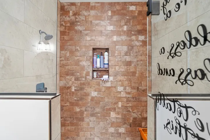 Shower with a built-in niche, brick-patterned tile, and a fixed showerhead