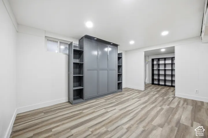 Recessed lighting, wood-finish flooring, built-in storage shelving, and a built-in wall bed
