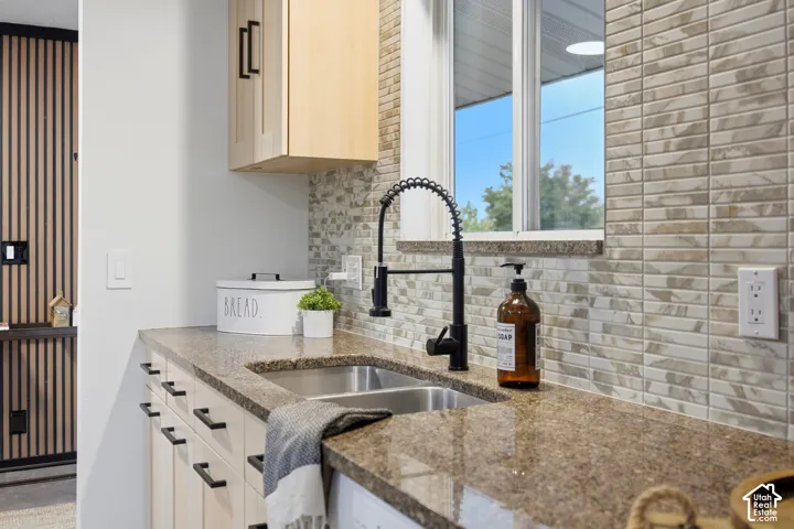 Dual basin stainless steel sink with a matte black high-arc faucet, complemented by a light-toned tile backsplash