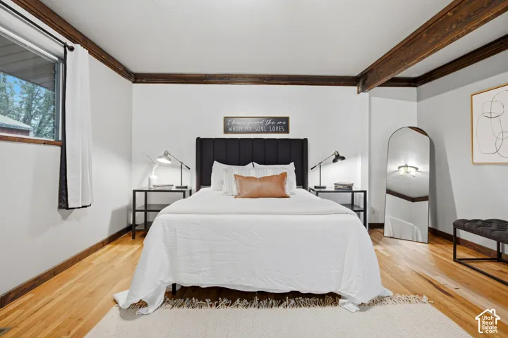 Exposed wood ceiling beams, wood-finish flooring, and a window with trim
