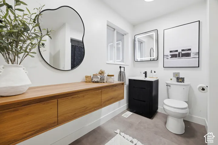 Floating wood-finish vanity with integrated drawers, modern black vanity with basin sink, illuminated rectangular mirror, and a contemporary wall-mounted mirror