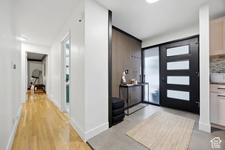 Entryway featuring a modern black door with frosted glass panels, an adjacent full-height frosted glass sidelight, wood-finish wall paneling, and a contemporary console table