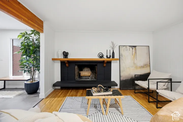 Hardwood flooring, painted brick fireplace with hearth, wood mantel, and wood ceiling beam