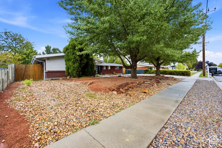 Front yard featuring mature trees and a rock landscaping bed