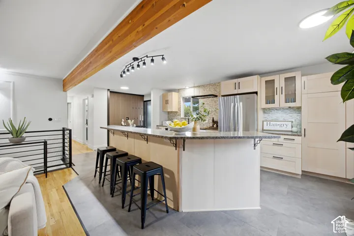 Kitchen with a substantial island, light-toned cabinetry, stainless steel appliances, and a tiled backsplash