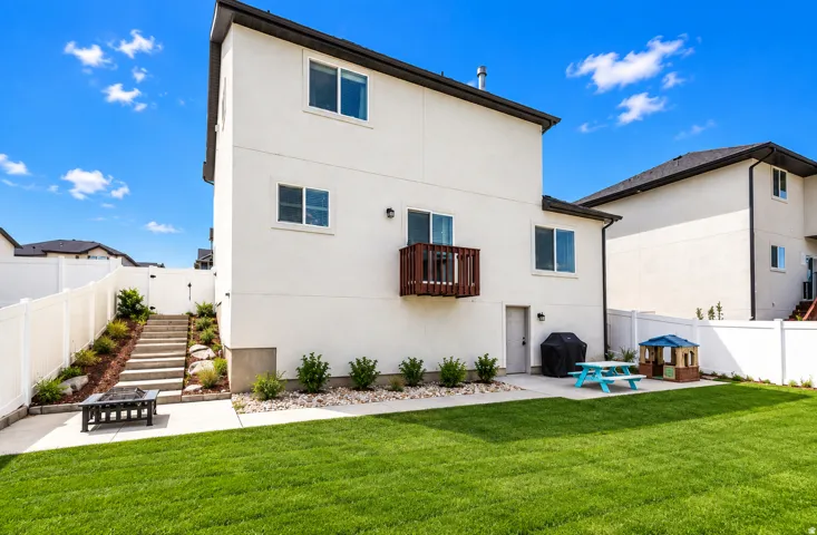 Expansive green lawn with a privacy fence, concrete patio, and a tiered landscaped area with stairs