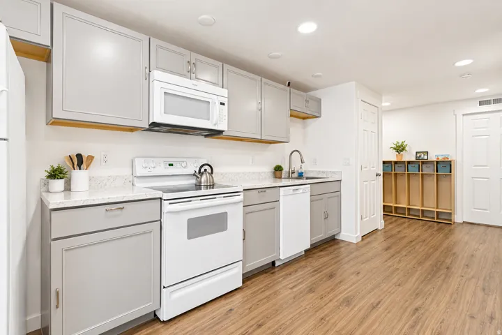 Kitchen featuring light gray cabinetry, white countertops, stainless steel sink, white electric range, and wood-finish flooring
