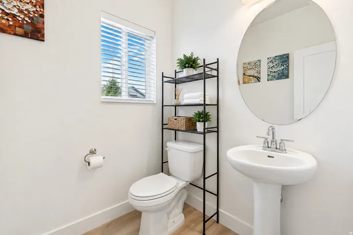 White pedestal sink, chrome fixtures, and circular wall mirror