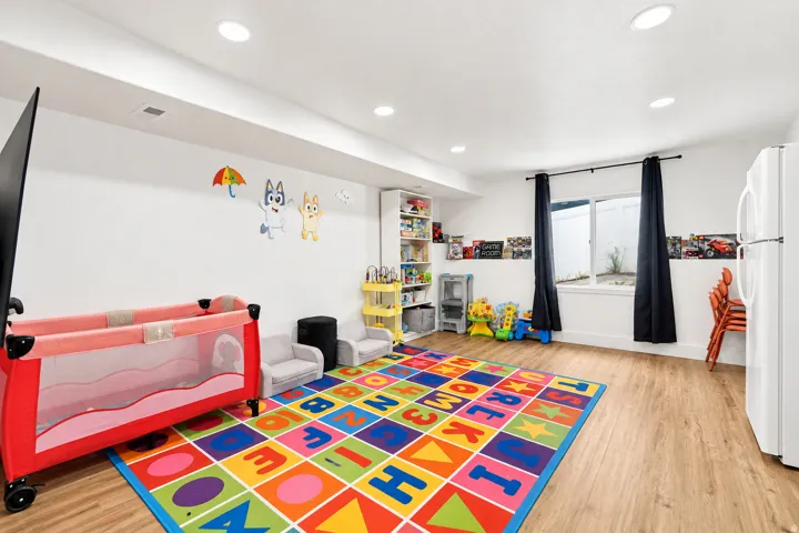 Recessed lighting, wood-finish flooring, built-in shelving, and a dual-pane window with black curtain rods