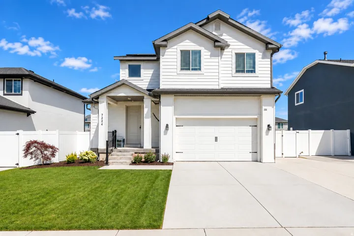 Contemporary two-story exterior with white siding, an attached garage, a covered entry, and a concrete driveway