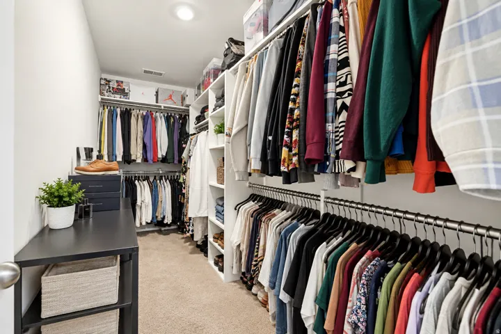 Custom closet system featuring extensive hanging rods, multiple shelving units, and a central storage island