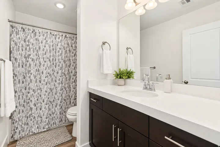 White countertop vanity with an integrated sink, dark wood-finish cabinetry, and a chrome faucet