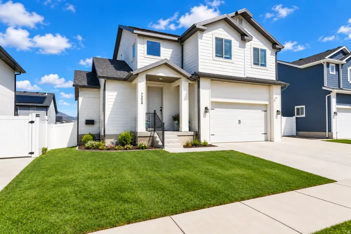 Contemporary two-story residence featuring white siding, a covered entry, and an attached two-car garage