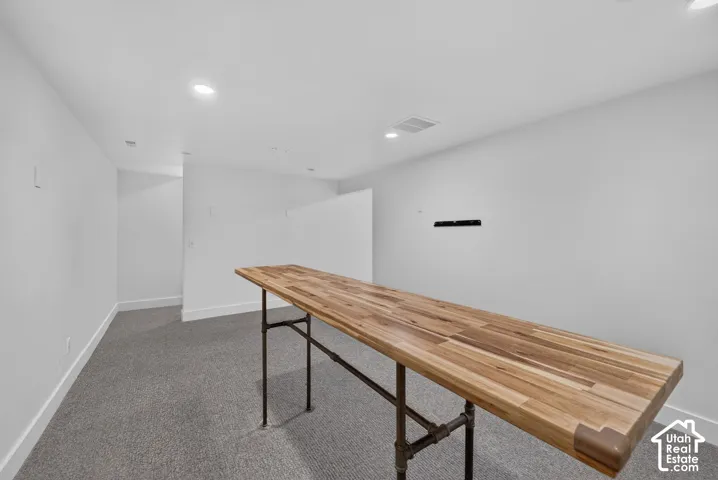 Recessed lighting, light gray carpet, white walls, and a wood-finish countertop