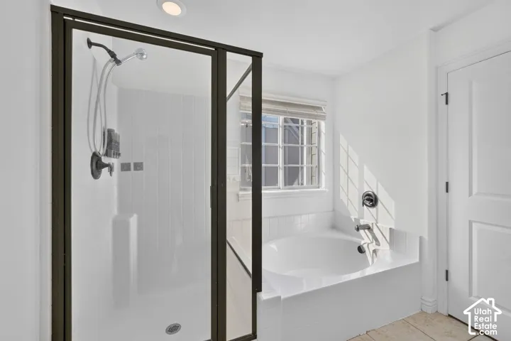 Enclosed shower with dark bronze framing, an integrated bathtub, and a window