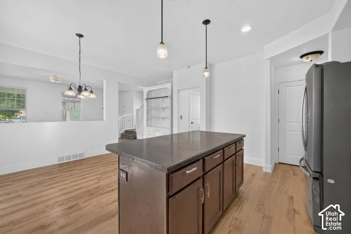 Kitchen island featuring a dark countertop, wood-finish flooring, and pendant lighting