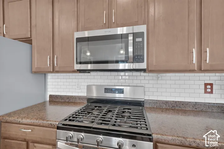 Wood-finish cabinetry paired with stainless steel appliances, including an over-the-range microwave and gas range