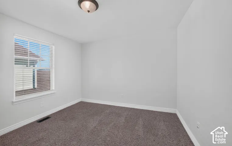 Neutral wall color, window with blinds, overhead lighting, and carpeted flooring