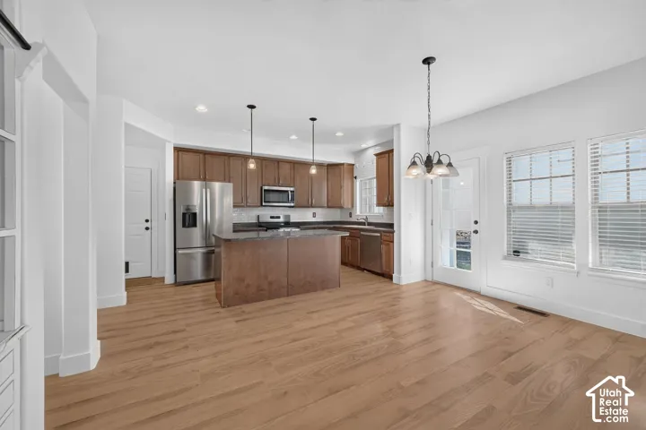 Open-concept kitchen and dining area featuring wood-finish flooring, recessed lighting, and a kitchen island with pendant lighting