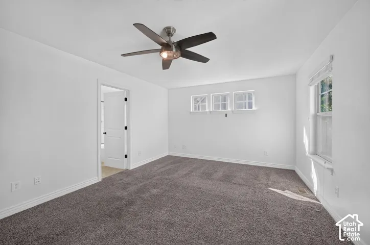 Neutral paint palette, ceiling fan with integrated lighting, multiple windows, and carpeted flooring