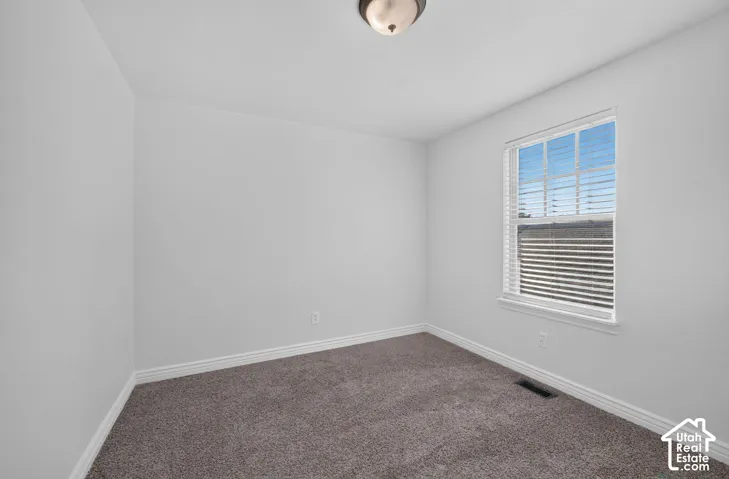 Room with neutral wall paint, gray carpet, and a single window with blinds