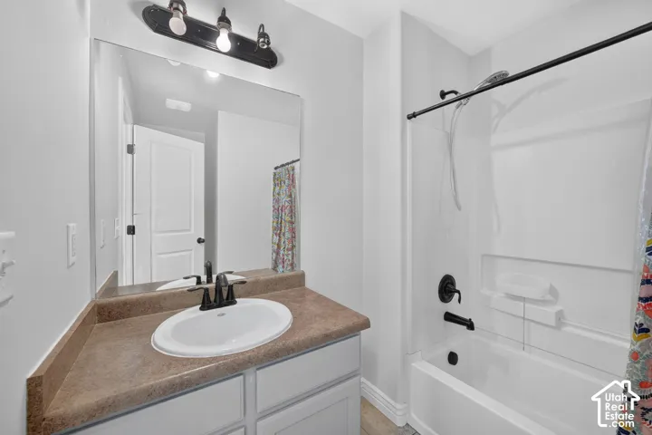 White vanity with a neutral-toned countertop and an oval undermount sink, complemented by a matte black faucet