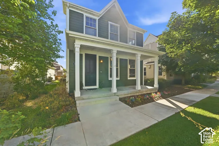 Two-story exterior with dark green siding, white trim, and a covered porch supported by four columns