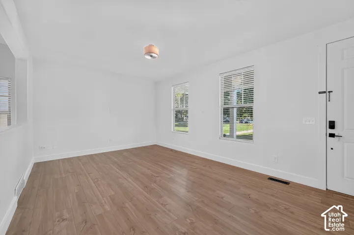 Expansive room featuring wood-finish flooring, white walls, and two windows with blinds
