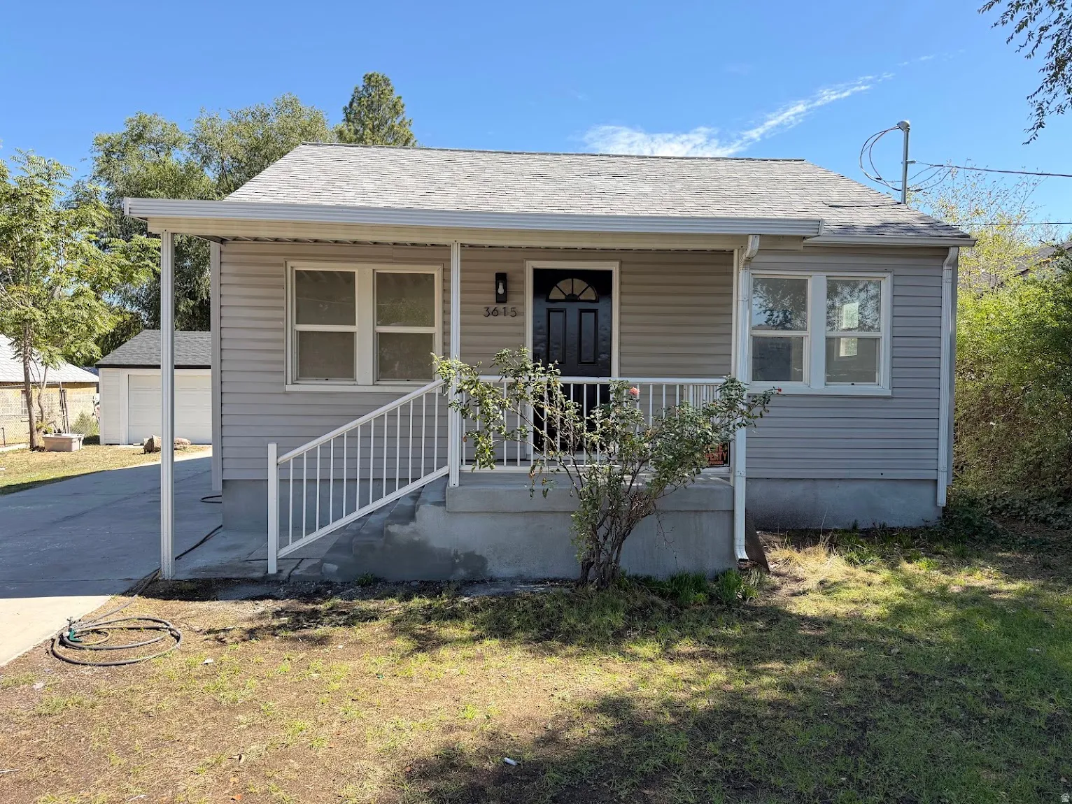 Light gray siding exterior with a covered porch, white railing, and a dark entry door