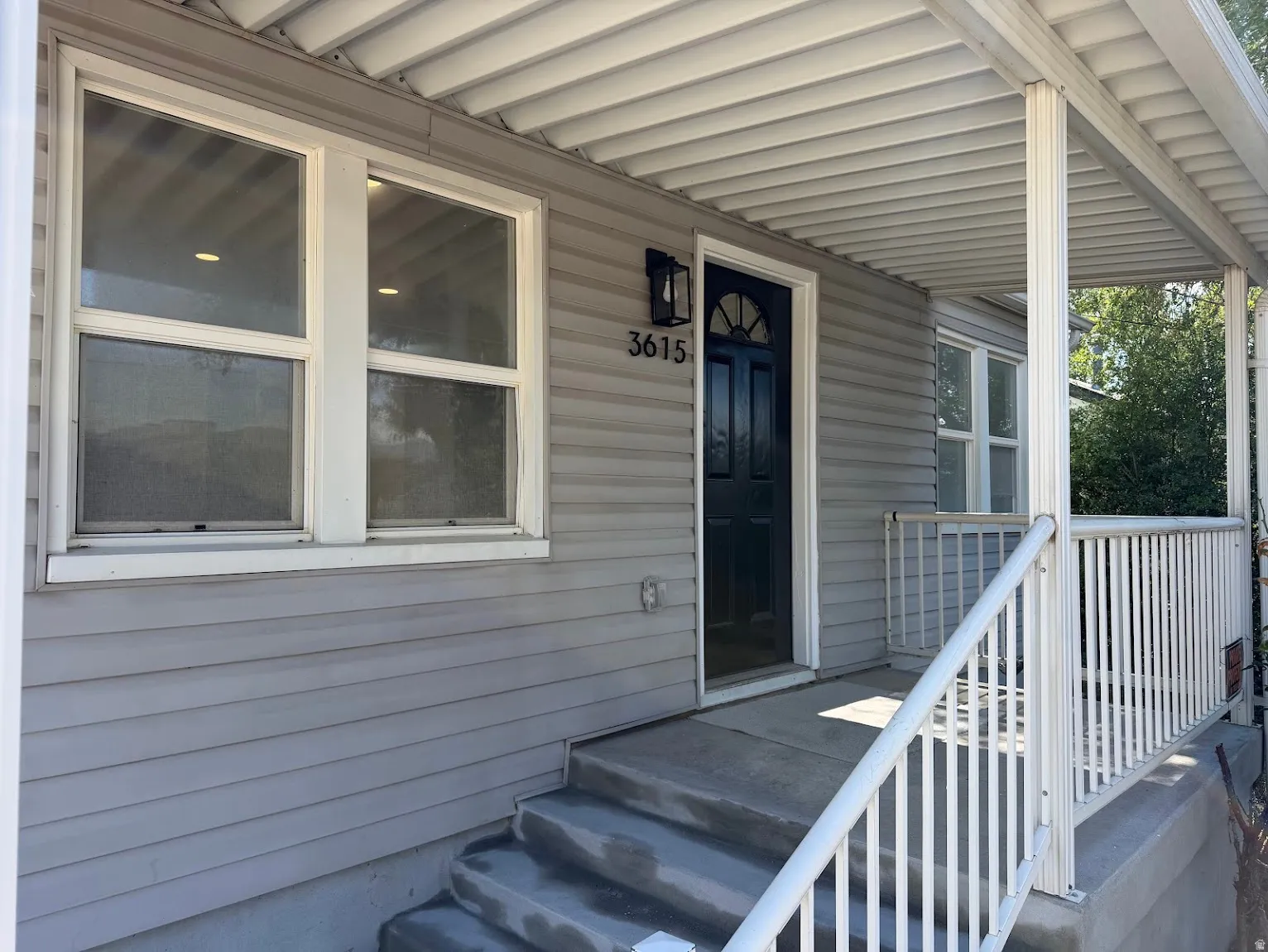 Covered front porch with white railings and support columns