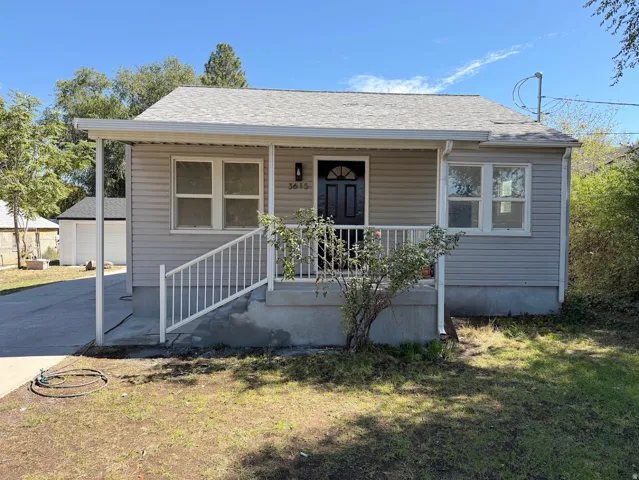 Light gray siding exterior with a covered porch, white railing, and a dark entry door