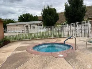 Outdoor spa with surrounding concrete patio and metal safety railing