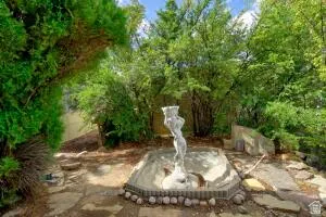 South West Lot corner  area featuring a central fountain with a statuary, surrounded by mature trees and flagstone paving