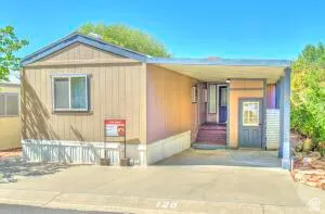 Front of the home showing a blue door shed entry featuring vertical siding, a covered entry, and a carport