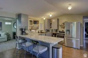 Kitchen featuring an granite countertop with seating, integrated stainless steel appliances.