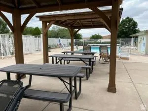 Covered patio with multiple picnic tables and a swimming pool