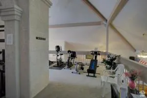 North side exercise room.  Vaulted ceiling with exposed beams, interior balcony overlooking the space, and a neutral color palette throughout