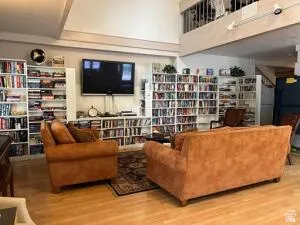 TV &  movies, internet or social area,  library and information,  Hardwood flooring, vaulted ceiling, built-in shelving, track lighting, and an upper-level balcony where Exercise equipment is located