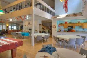 Open-concept living area with wood-finish flooring, a double-height ceiling, a second-story interior balcony, a built-in fireplace, and an integrated kitchen with wood cabinetry, Dining area and 2nd floor exercise area balcony.