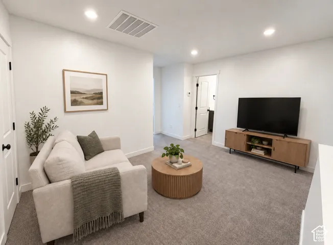 Recessed lighting, light gray carpeting, crisp white walls, and a built-in media console
