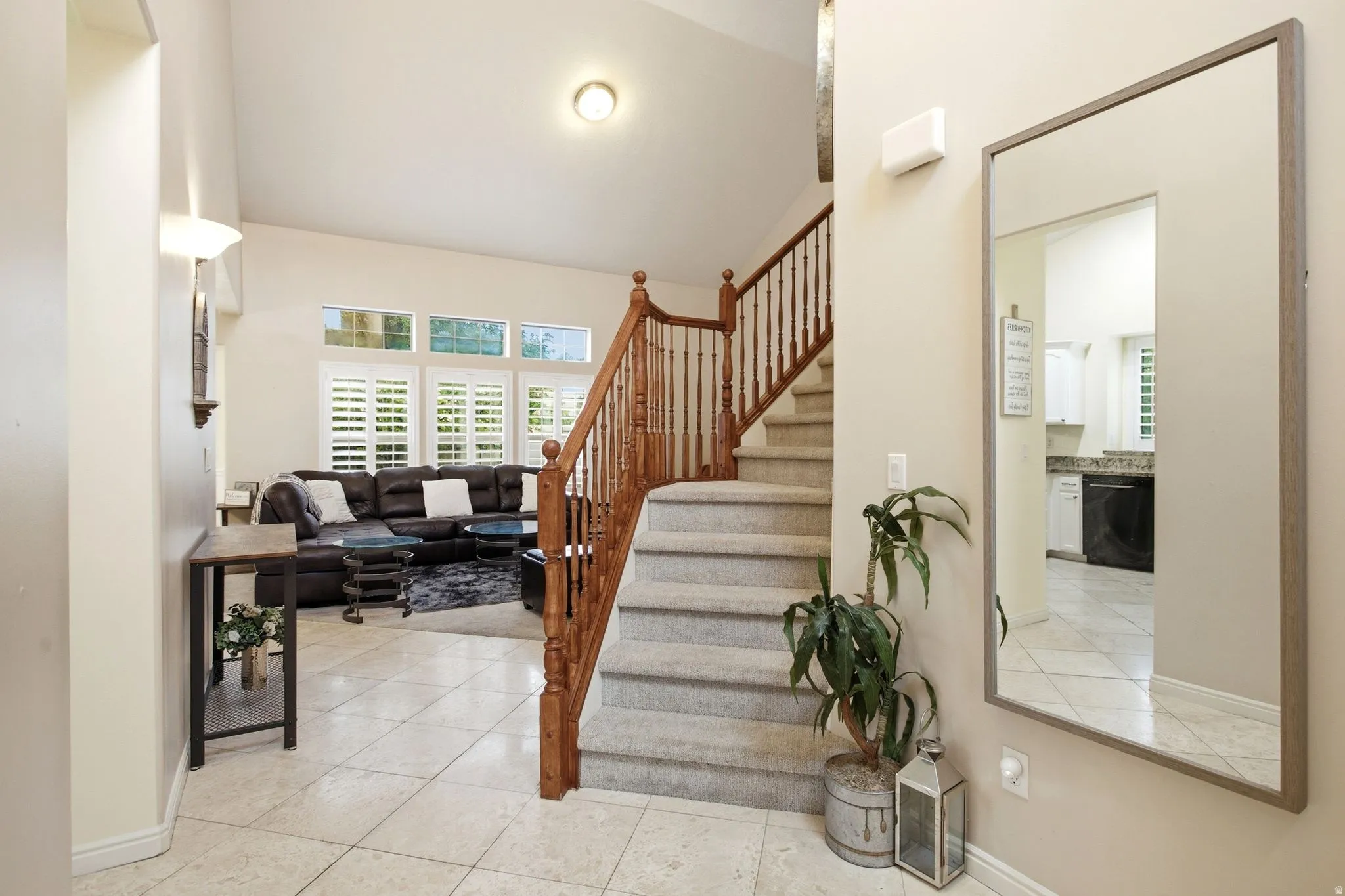 Welcoming foyer featuring tile flooring, a large framed mirror, and a decorative plant accent