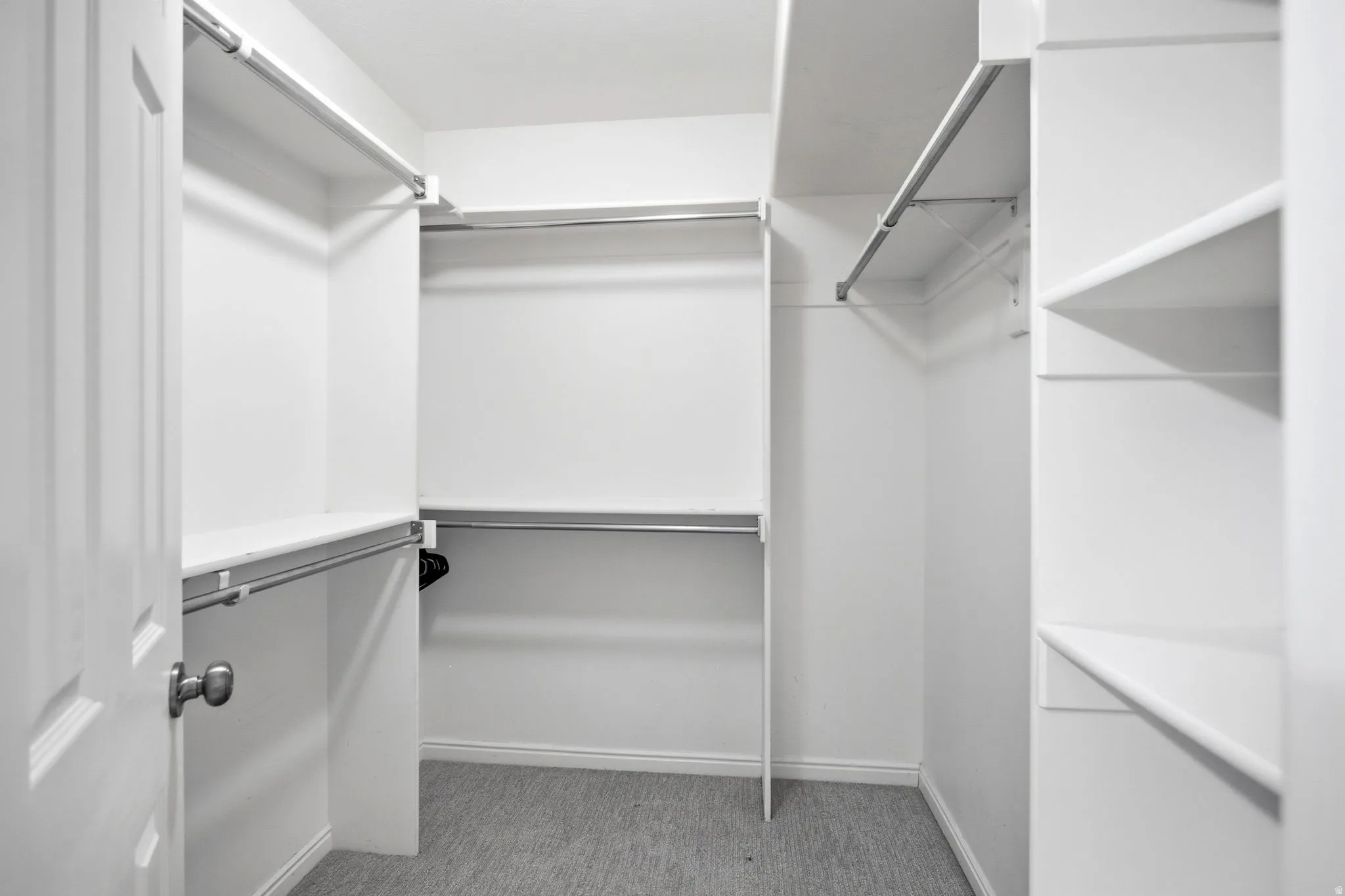 Spacious walk-in closet featuring double hanging rods, multiple shelving units, and abundant storage capacity with neutral finishes and clean lines throughout