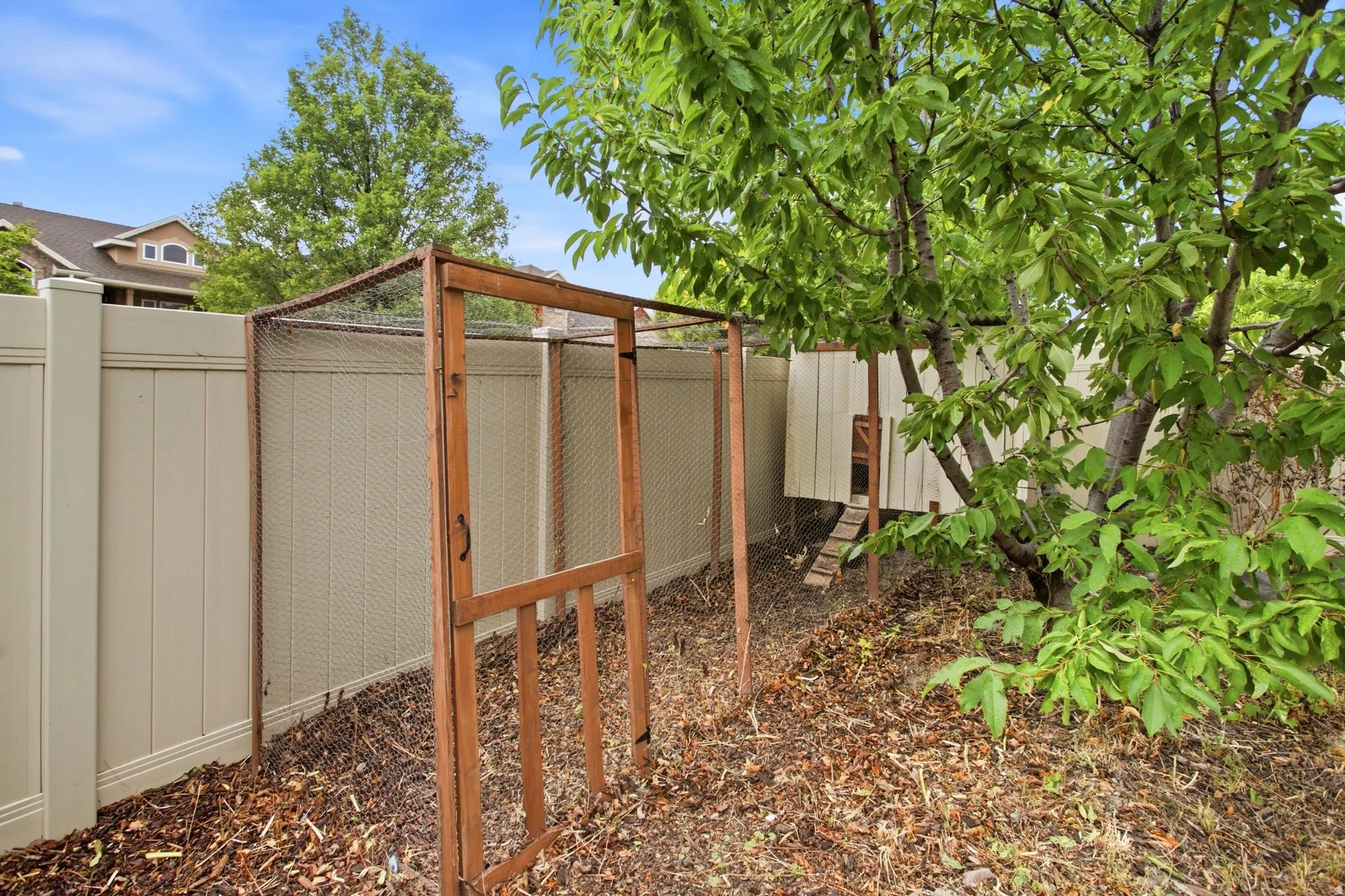Secure backyard retreat featuring a wood-frame enclosure with mesh screening, gravel ground cover, and mature shade trees