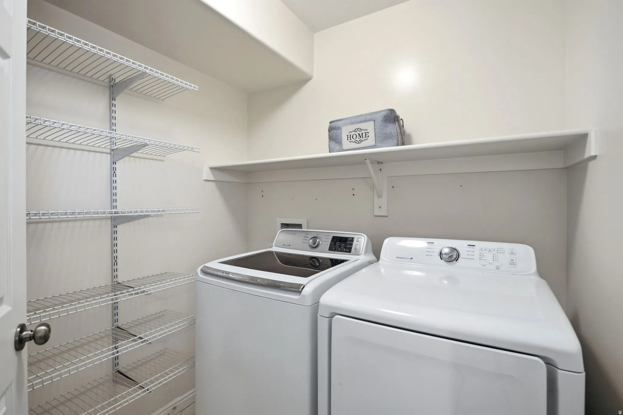 Laundry area with wall-mounted wire shelving and an upper storage shelf