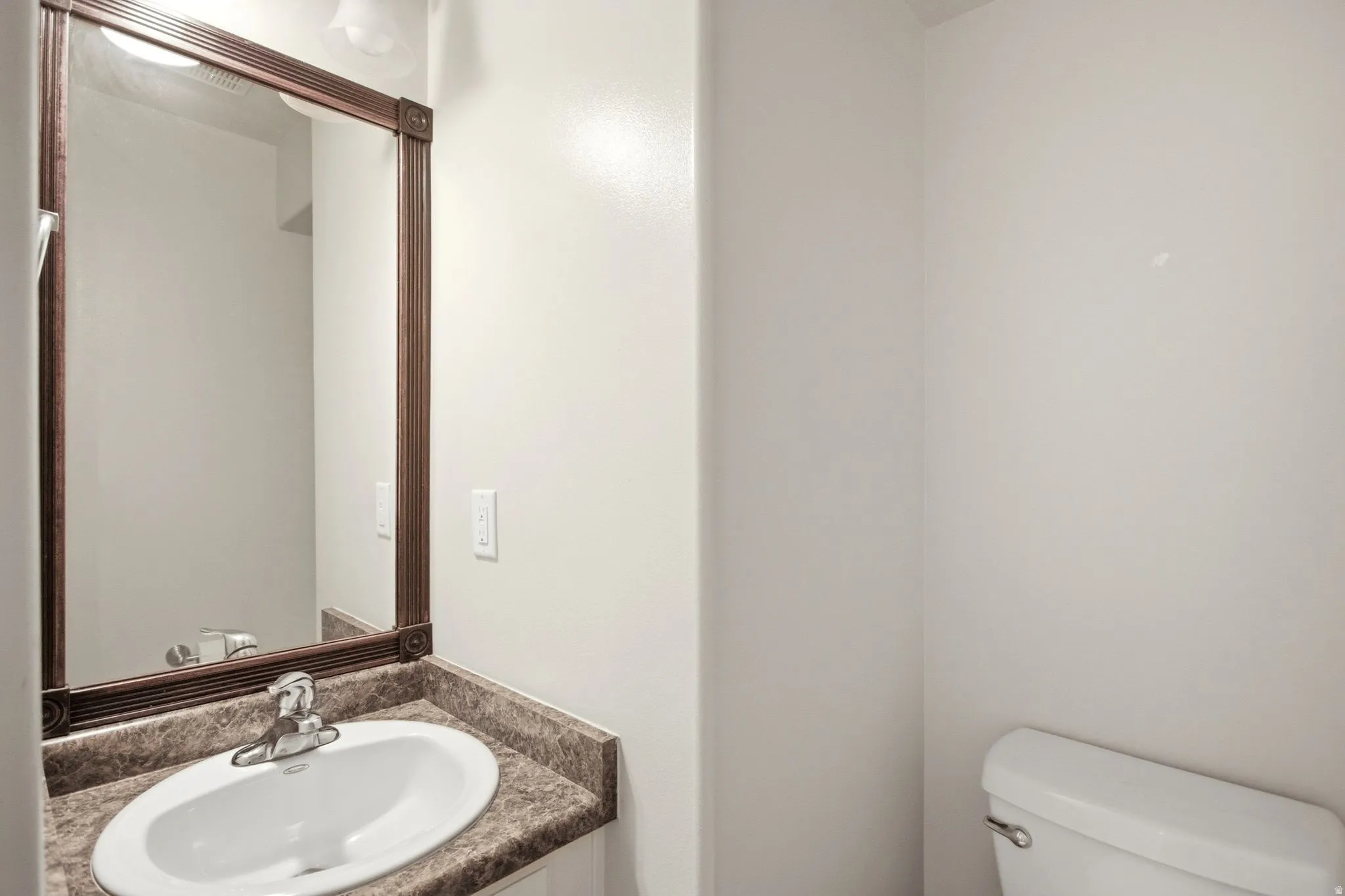 Bathroom featuring a vanity with a laminate countertop, an oval undermount sink, and a framed mirror