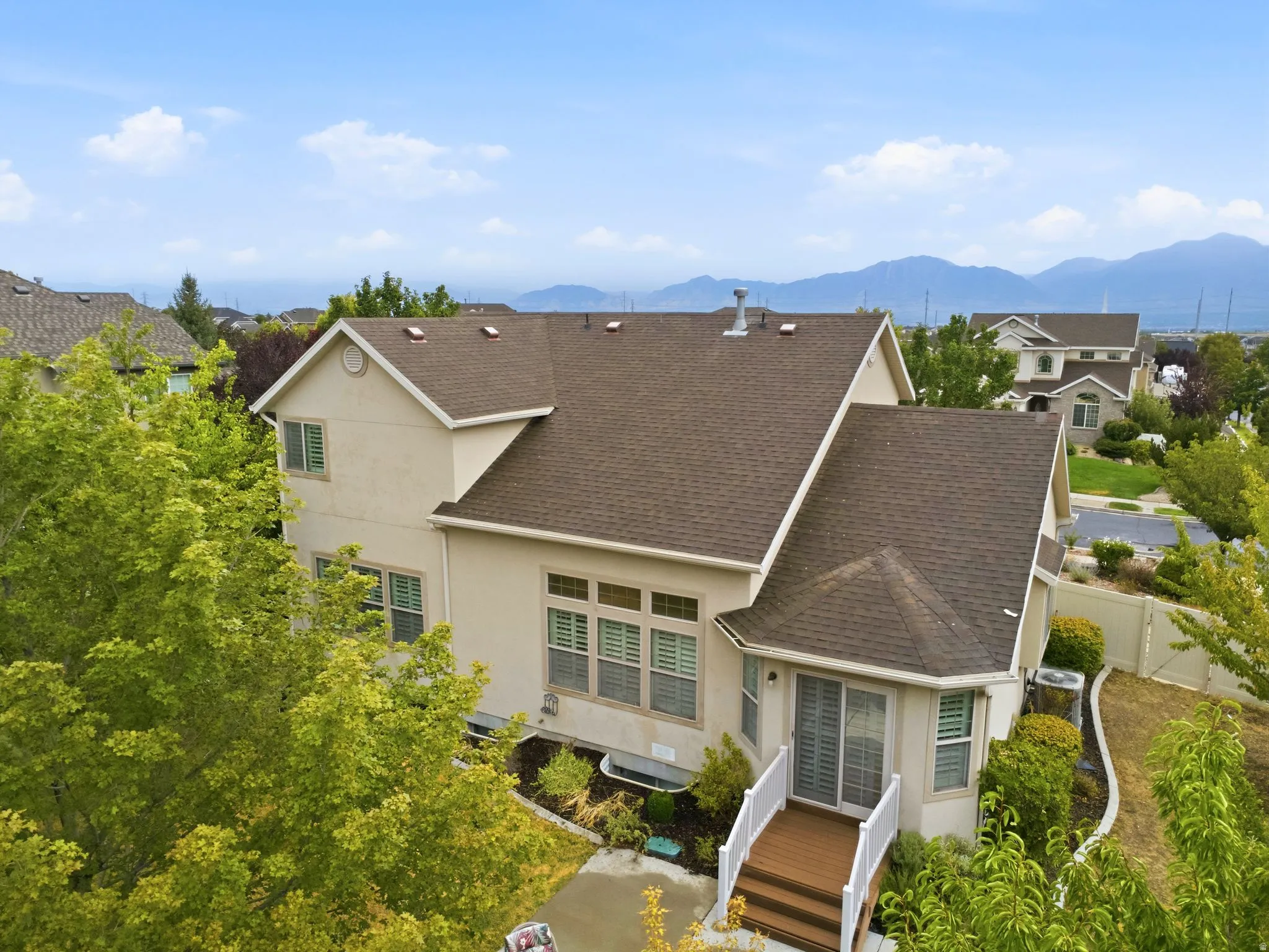 Elegant two-story residence featuring a steeply pitched architectural roof design with multiple gables, neutral exterior siding, and dark asphalt shingle roofing