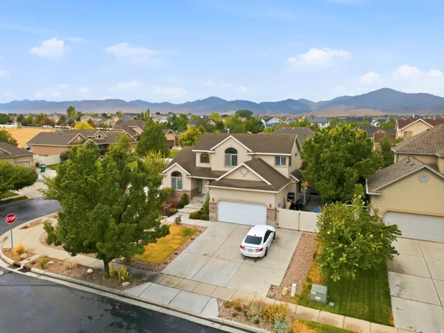 Two-story stucco exterior with arched windows, attached two-car garage, concrete driveway, and mature landscaping